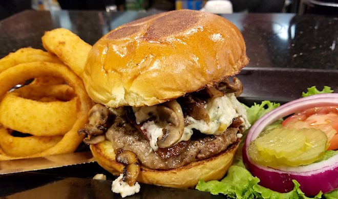 Build Your Own Burger with 44 Farms Burger with aged Blue Cheese, Mushrooms, Peppered Bacon on a Brioche Bun with a side of hand battered onion rings at Omega Grill