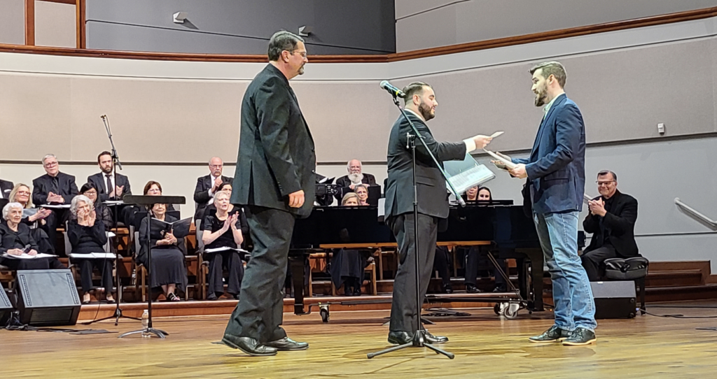 Conroe-area emerging composer, Travis Redden, accepts an award from Montgomery County Choral Society board president, Matthew Ciesko, and Artistic Director, Dr. Robert Horton.