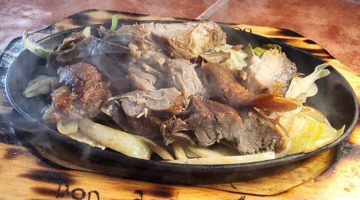 Housemade Carnitas - Perfectly slow roasted pork Carnitas on a sizzling platter. served with rice, bean soup, pico de Gallo, guacamole and tortillas. Photo by Nick Rama.