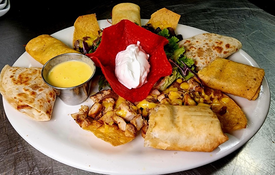 Fiesta sampler - combination of mixed fajita nachos ,chicken quesadillas, mini chimichanga,and chicken flautas, served with sour cream , jalapeños and queso Photo by Nick Rama.