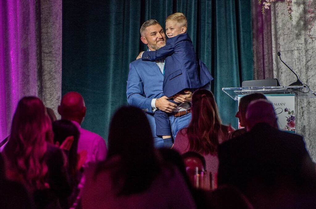 Photo caption: Taylor Odlozil shares his caregiver’s story and welcomes son Weston to the stage. His
wife Haley who passed away from ovarian cancer spoke at the event in 2016.