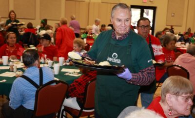 Ray Sanders, a member of Interfaith’s Board of Advisors, serves a warm meal to seniors at the Holiday GIVING Lunch